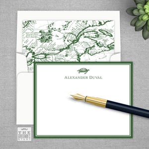 May include: A white card with a green border and a green turtle illustration. The text "Alexander Duval" is printed in green below the turtle. The card is on a gray textured surface.