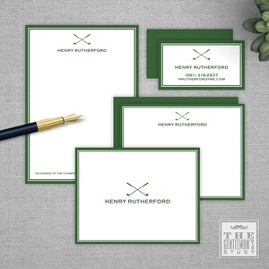 May include: Stationery set featuring a white background with a green border. The set includes a notepad, notecards, and business cards. The text "HENRY RUTHERFORD" and crossed golf clubs are printed on each item. A black and gold pen is on the left.