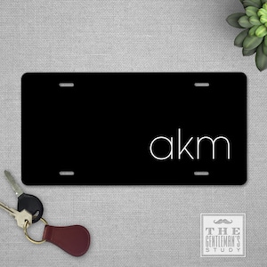 May include: Black license plate with white letters spelling "akm".