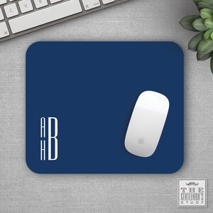 May include: A navy blue mouse pad with white monogram initials "A H B" and a white wireless mouse on top.