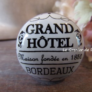 May include: White ceramic knob with black lettering that reads "Grand Hôtel Maison fondée en 1852 Bordeaux" and "Le Grenier de la Pie".