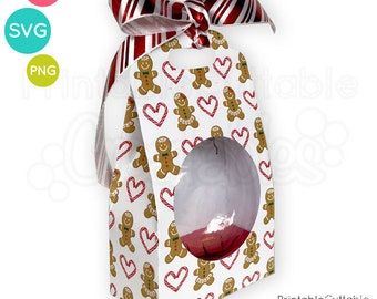 May include: A white gift box with a window, decorated with a gingerbread man pattern and red candy cane hearts. The box has a red and white striped ribbon tied around it.
