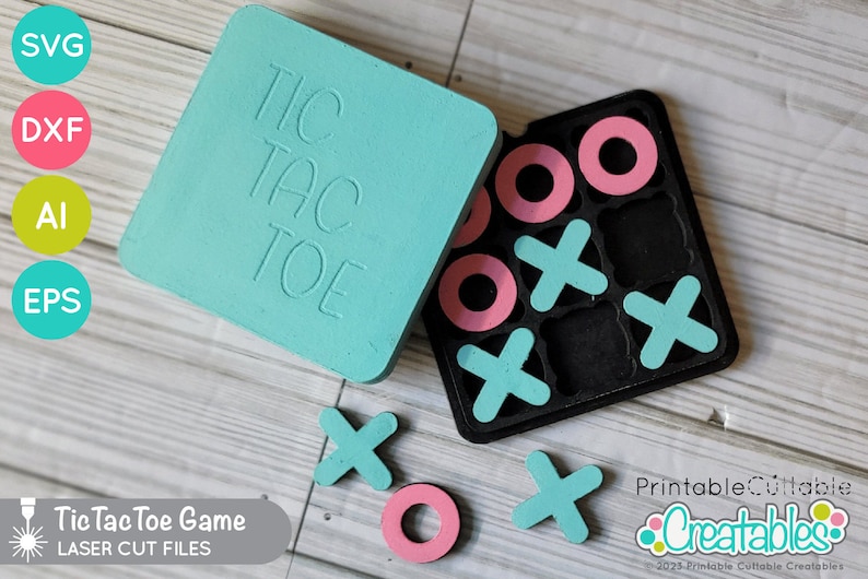 May include: A teal blue Tic Tac Toe game with a black game board and pink and teal game pieces. The game board is labeled "Tic Tac Toe". The game pieces are circles and X's. The game is made of wood and is laser cut.