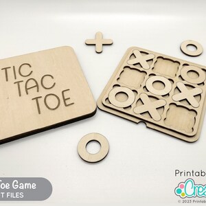May include: A wooden Tic Tac Toe game with a board, nine playing pieces, and a separate piece with the words "Tic Tac Toe" engraved on it. The game is made of natural wood and has a light brown color.
