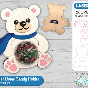 Peut inclure: Un porte-bonbons en forme d'ours polaire blanc avec une écharpe bleue et des pattes roses. L'ours tient un dôme transparent rempli de bonbons colorés. L'image comprend le texte "Polar Bear Dome Candy Holder" et "LASER CUT FILES".