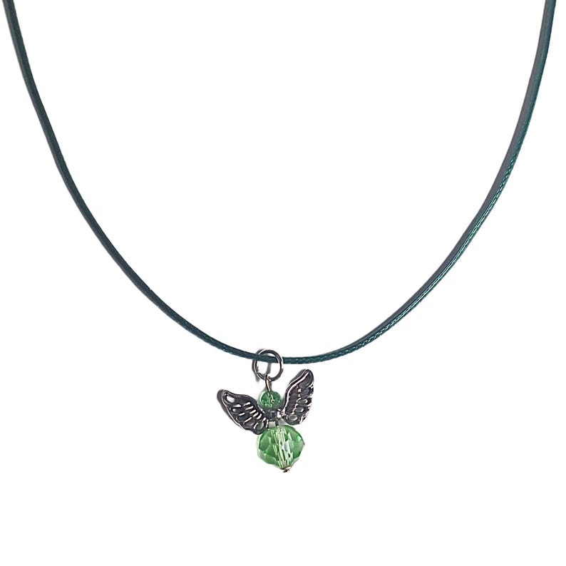 Puede incluir: Un collar con un colgante de &aacute;ngel de cristal verde en un cord&oacute;n verde oscuro.
