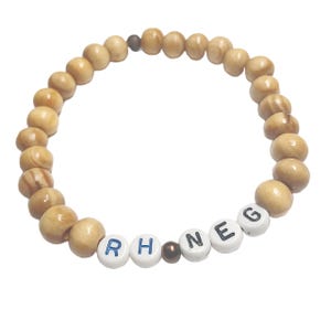 May include: A wooden bead bracelet with the letters "RH NEG" spelled out in white beads with blue lettering.