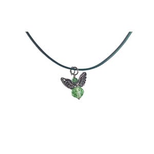 Puede incluir: Un collar con un colgante de &aacute;ngel de cristal verde en un cord&oacute;n verde oscuro.