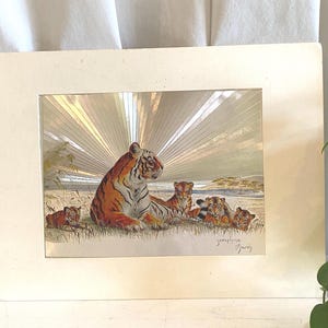 May include: A rectangular print featuring a large tiger and four cubs resting in tall grass. The background displays a metallic sunburst effect with radiating silver lines. The artist signature Josephine Marsh is visible in the bottom right corner.