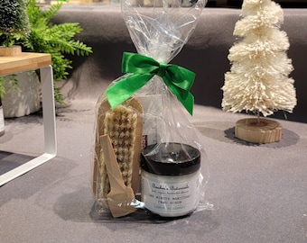 Può includere: Un sacchetto di plastica trasparente legato con un nastro verde contiene un piccolo pennello di legno, uno spingicuticole di legno e un piccolo barattolo di scrub per le mani. Il barattolo è etichettato "Brewer's Botanicals One Minute Manicures Hand Scrub Lemon Rosemary".