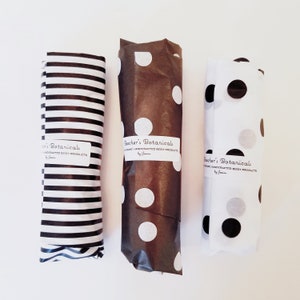 May include: Three rolls of brown and white patterned wrapping paper with black and white stripes, white polka dots, and black and white polka dots. Each roll has a label that reads "Bacher's Botanicals Organic Handcrafted Body Products by Janine."