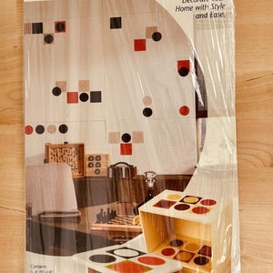 May include: Stencil Decor kit with mylar sheets. The package shows a variety of geometric shapes in red, black, and beige. The text reads "Decorate Your Home with Style and Ease."