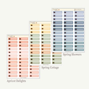 Op de afbeelding: Drie vellen stickers met rechthoekige labels in pastelkleuren. Elk label heeft een klein bruin pictogram. De vellen zijn gelabeld met "Apricot Delights", "Spring Cottage" en "Spring Showers". De stickers zijn voor planning en organisatie.