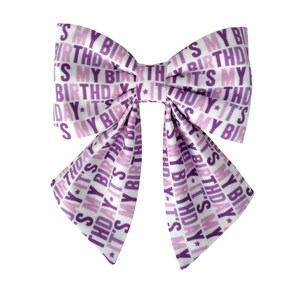 Peut inclure: Un nœud pour cheveux en tissu avec un motif répétitif du texte IT'S MY BIRTHDAY dans des nuances de violet sur fond blanc. Le nœud présente deux grandes boucles supérieures et deux longs pans pointus tombant vers le bas, tous imprimés.