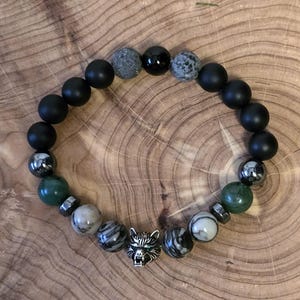 May include: Black, green and grey beaded bracelet with a silver wolf charm.