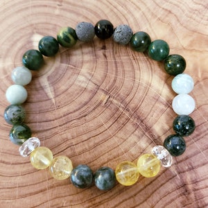 May include: A green, yellow, and white beaded bracelet with a variety of stones, including clear quartz, lava rock, and aventurine.