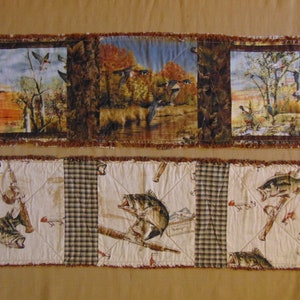 Może przedstawiać: Brązowy, beżowy i biały pikowany bieżnik stołowy z patchworkowym wzorem przedstawiającym obrazy kaczek, ryb i kratę.