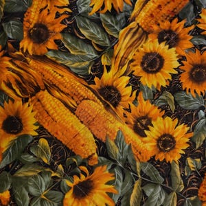 May include: A quilted fabric with a pattern of sunflowers and corn. The sunflowers are yellow and orange, with green leaves. The corn is a golden yellow colour. The background is dark.