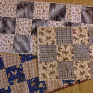 May include: Three patchwork quilt squares with a black and white gingham pattern, a white background with brown and white chickens, and a white background with brown and white horses. The squares are sewn together with a brown fabric border.