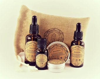 Puede incluir: Un conjunto de productos para el cuidado de la barba en botellas de vidrio marrón con goteros y una lata de metal. Las botellas y la lata tienen etiquetas con el texto "Double Sunnah" y "Beard Oil" o "Beard Balm". Los productos están dispuestos sobre una superficie de arpillera.