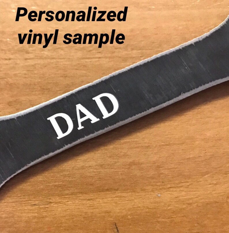 K&ouml;nnte beinhalten: Ein personalisierter Schraubenschl&uuml;ssel aus Metall mit dem Wort "DAD" in wei&szlig;er Vinylfolie.