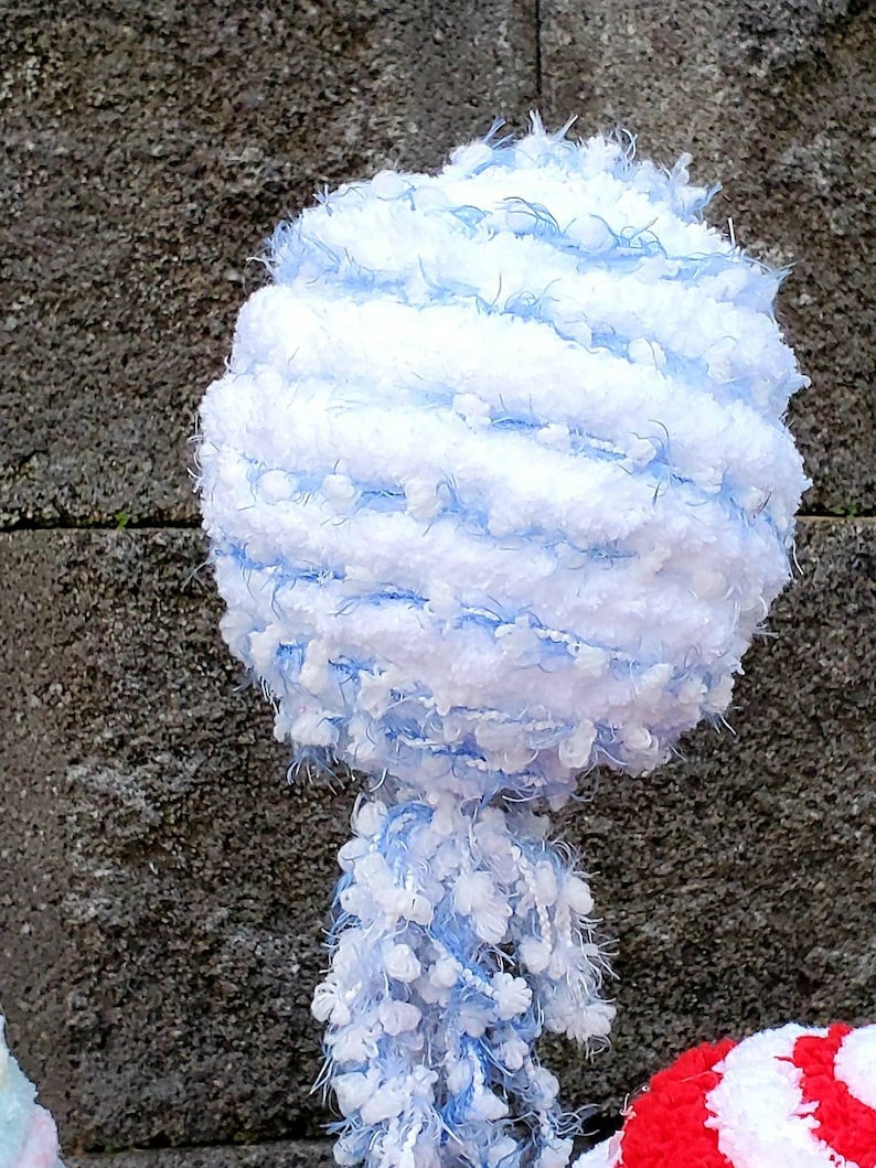 May include: A white and light blue fluffy yarn ball with a long, fluffy tail. The yarn ball is made of a soft, fuzzy material and has a light blue and white striped pattern.