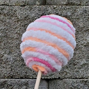 May include: A pink, orange, and white striped cotton candy toy on a wooden stick.