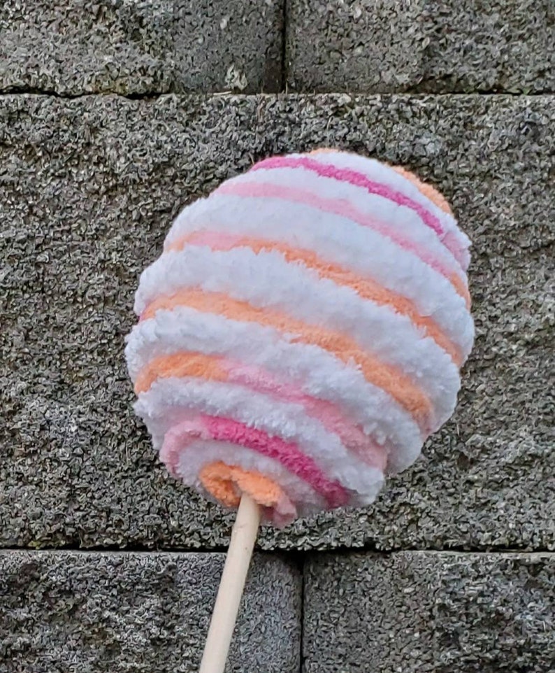 May include: A pink, orange, and white striped cotton candy toy on a wooden stick.