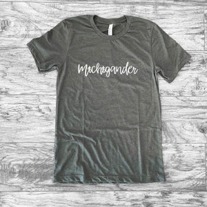 Puede incluir: Una camiseta gris jaspeada con la palabra "Michigander" en escritura blanca en el pecho. La camiseta tiene cuello redondo y mangas cortas. La tela parece suave y c&oacute;moda.