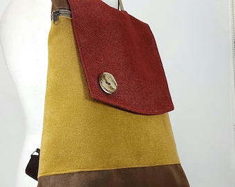 May include: A brown, yellow, and red canvas backpack with a large flap and a wooden button closure.