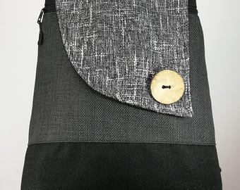 May include: A gray and black backpack with a textured fabric design. The flap features a white and gray pattern and a large wooden button closure. The backpack has a black handle and zipper.
