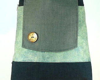 May include: A handmade backpack with a flap closure and a large wooden button. The bag features a color block design with shades of green and black. The top handle and the flap are a darker green, while the main body has a textured, marbled appearance.