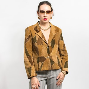 Peut inclure: Un blazer en daim marron avec un motif patchwork dans différentes nuances de marron et de vert. Le blazer a un col cranté, deux boutons et une coupe ajustée. Le modèle porte des bijoux et des lunettes de soleil dorés.