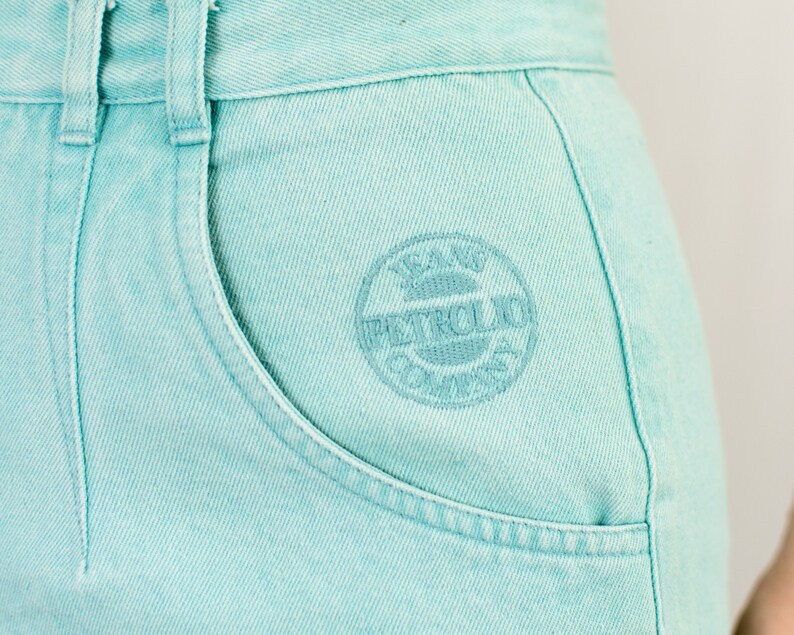 Puede incluir: Pantalones cortos de mezclilla azul claro con un logotipo bordado en blanco que dice "Jeans Petrol Club".