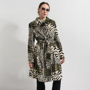 May include: A long coat with a patchwork design featuring animal prints like zebra and leopard. The coat has a belted waist, a collared neckline, and button closures. The color palette includes black, white, and olive green.