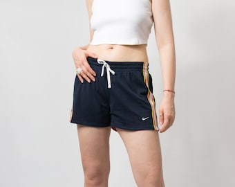 May include: Navy blue athletic shorts with white drawstring and side stripes in pink, yellow, and red. The shorts have a white Nike logo on the right leg.