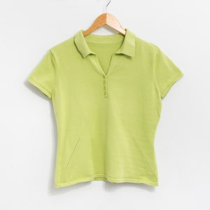 K&ouml;nnte beinhalten: Ein hellgr&uuml;nes, kurz&auml;rmeliges Poloshirt mit Knopfleiste und einem Holzb&uuml;gel.