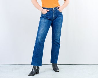 May include: A pair of blue denim jeans with a frayed hem, worn with black boots.