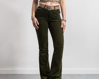 May include: Dark olive green corduroy pants featuring a mid-rise waist, a classic five-pocket design, and a straight-leg cut. The pants are secured with a tan leather belt that has a silver-toned metal buckle and matching silver-toned hardware.