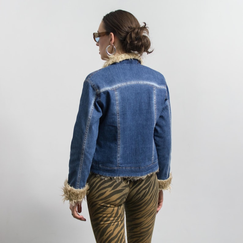 Peut inclure: Veste en jean bleue avec un col et des poignets en fausse fourrure marron clair. La veste a un design classique avec une fermeture boutonn&eacute;e et une coupe ajust&eacute;e. Le mod&egrave;le porte un pantalon &agrave; imprim&eacute; z&eacute;br&eacute; marron.