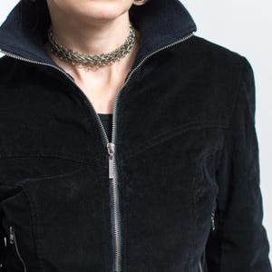 Puede incluir: Chaqueta de pana negra con cremallera plateada y cuello acanalado. La chaqueta tiene una silueta entallada y un collar de cadena plateada. Un estilo cl&aacute;sico, adecuado para diversas ocasiones.