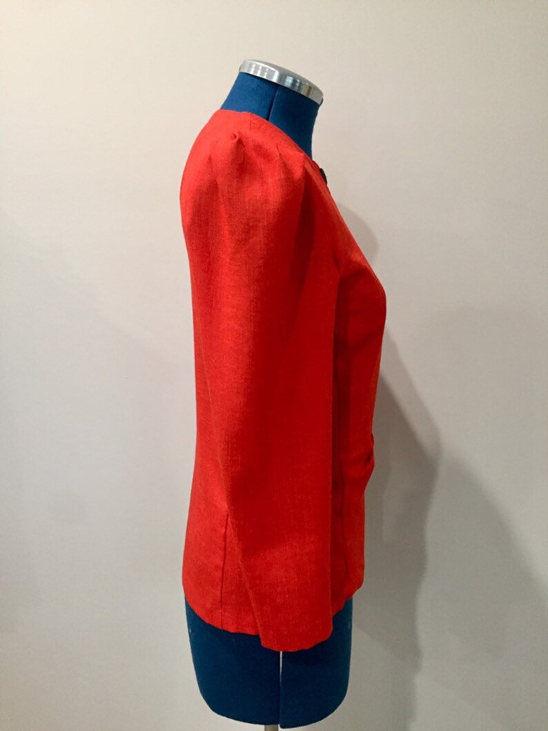 May include: A bright red blazer with a slightly puffed shoulder and a single button closure.