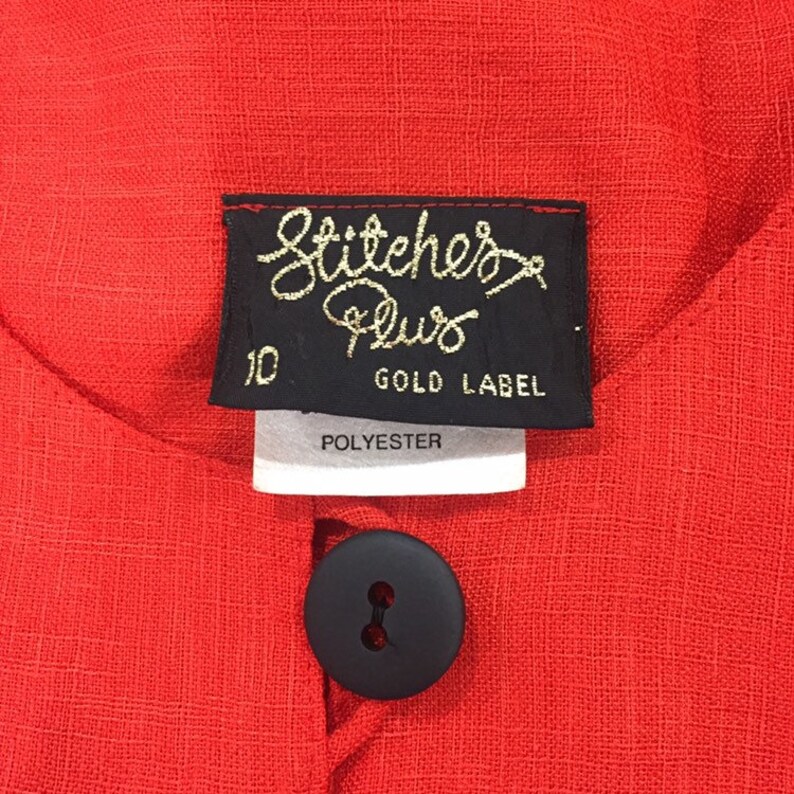 May include: Red polyester dress with a black button and a label that reads "Stitcher's Plus Gold Label" and "10".