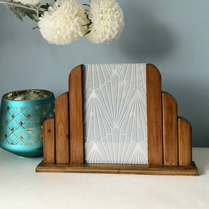 May include: A wooden picture frame with a white geometric design on the glass. The frame is in the shape of an arch and has a dark wood finish.
