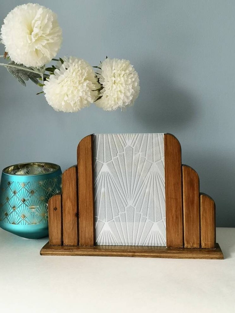 May include: A wooden picture frame with a white geometric design on the glass. The frame is in the shape of an arch and has a dark wood finish.