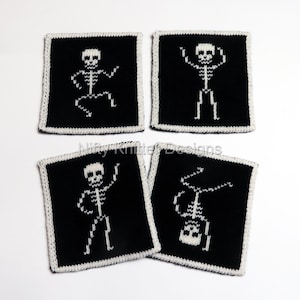 May include: A set of four square knitted coasters in black with white borders. Each coaster features a unique white skeleton graphic in a different dancing pose. The text Nifty Knitter Designs is centered across the middle of the four coasters.