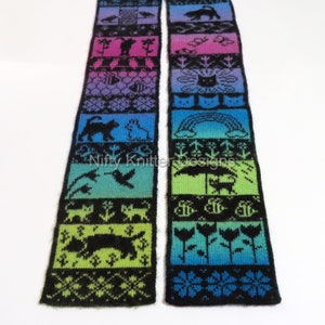 May include: Two knitted scarves with a colourful gradient design. Each scarf features a series of black silhouette images including cats, birds, and flowers. The text "Nifty Knitter Designs" is visible on the scarf.
