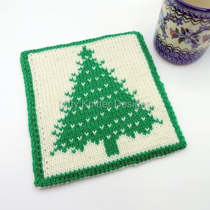 May include: A knitted green Christmas tree coaster with a white border. The coaster is made with a simple stitch pattern and is perfect for adding a festive touch to your home.