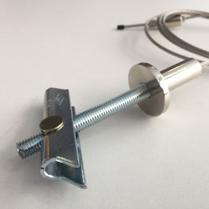 May include: A silver metal ceiling hook with a threaded rod and a metal plate. The hook is designed to be used with a wire cable.