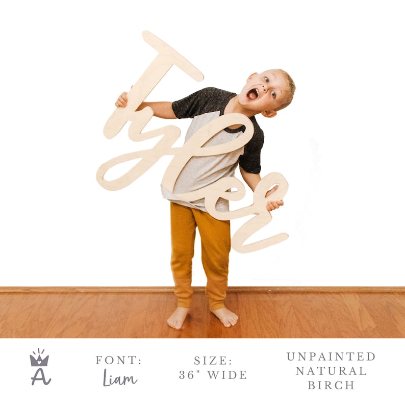 May include: A child holds up a large, wooden sign with the name "Tyler" written in a cursive font. The sign is 36 inches wide and made of natural birch wood. The sign is unpainted.